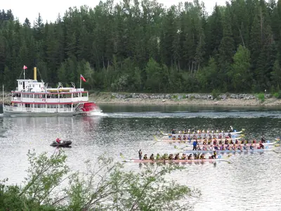 Dragon boats racing on a river past a paddle steamer