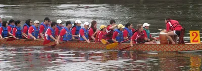 Paddlers in life jackets rowing hard in a long boat