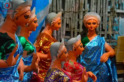 Clay idols in bright saris standing together in an artists workshop