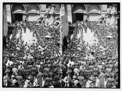 Black and white photo of a large crowd in an old church courtyard
