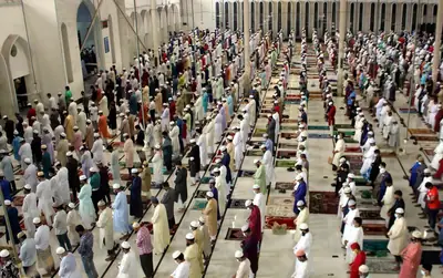 Long rows of men in prayer inside a large mosque courtyard