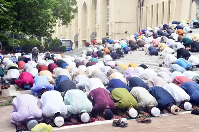 Worshippers bow in prayer on colourful mats outside a mosque