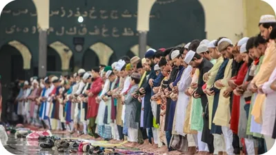 Long rows of worshippers in colourful clothes standing for prayer in a mosque courtyard