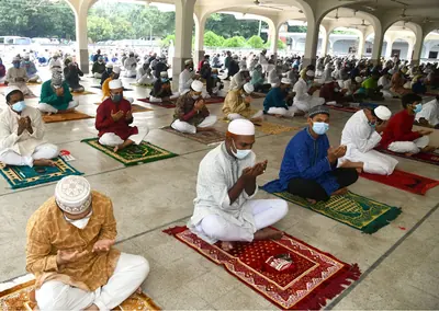 People pray on bright prayer mats under the arches of a mosque