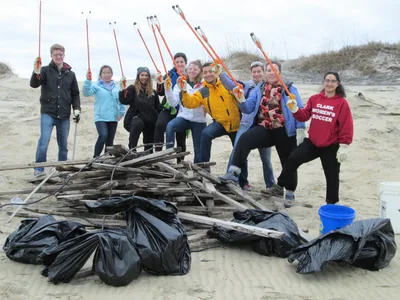 A happy group of volunteers with bags of rubbish on a beach