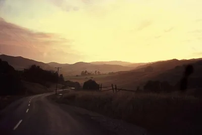 A quiet road leading towards the hills at sunset