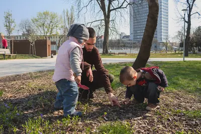 A grandfather and a young boy looking at the ground together in a park