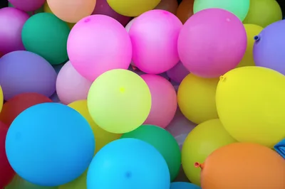 A heap of bright pink, yellow, blue and green balloons
