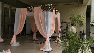 A decorated arch with peach curtains and fresh flowers at a party hall