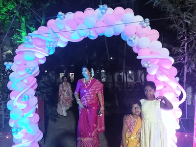 The entrance to a first birthday party under a pink and blue balloon arch at night