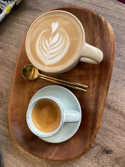Two cups of coffee with latte art on a wooden tray