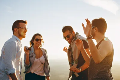 A group of friends laughing and talking in the evening sun