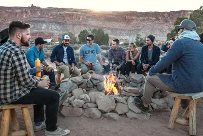 A group of friends sitting around a campfire among rocks in a desert valley