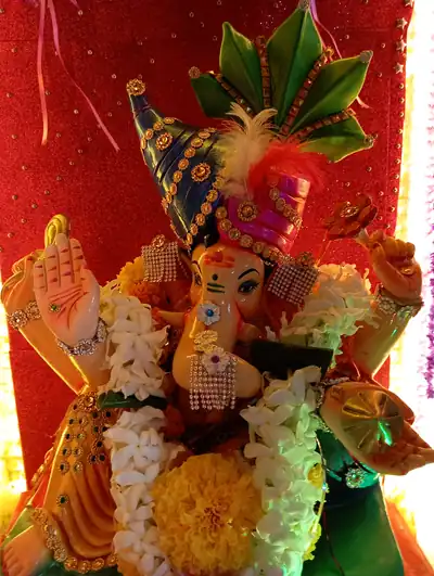 A colourful Ganesha idol with a jewelled crown, garlands of white and yellow flowers