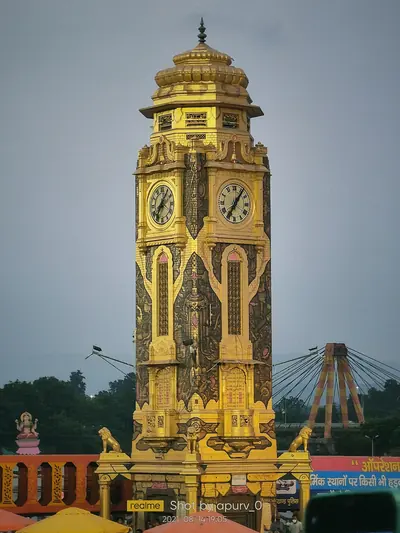 A tall golden clock tower standing by the river