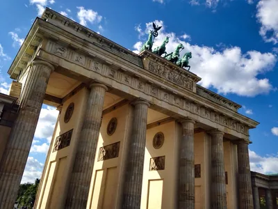The columns and horse statue of the Brandenburg Gate under a blue sky