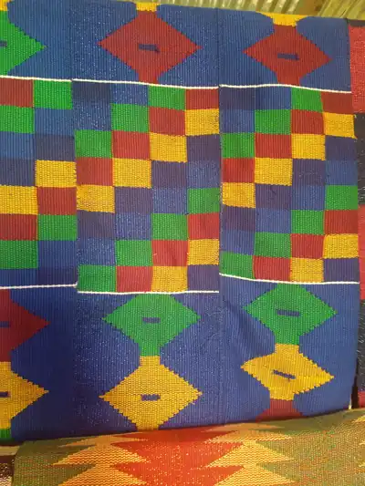 A close view of woven kente cloth in blue, green and yellow squares