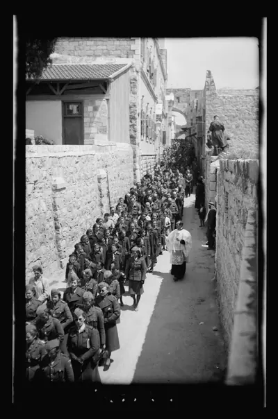 Black and white photo of a crowd walking a narrow stone lane