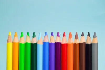 Coloured pencils standing in a row against light blue