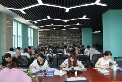 Students studying at long tables in a big library