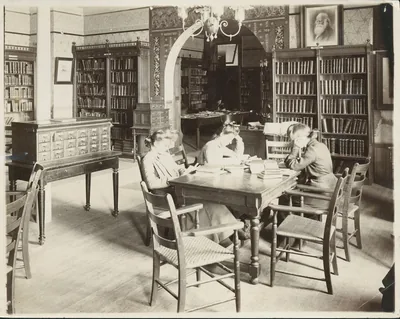 An old photo of three students reading in a library