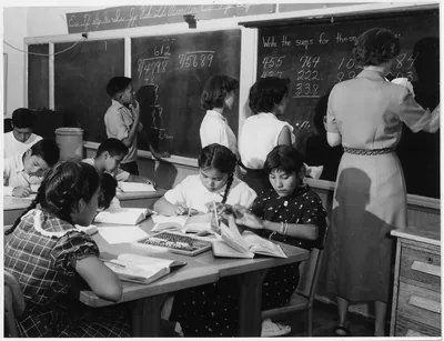 An old photo of students doing maths at a blackboard