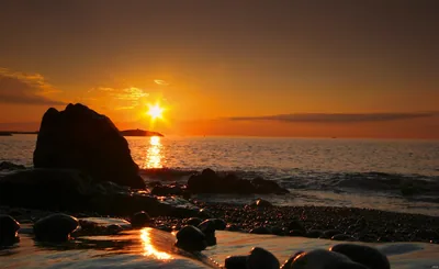 The sun rising over the sea and rocks