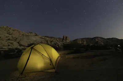 A glowing yellow tent under a starry sky
