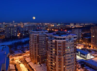 A full moon over a city at dusk