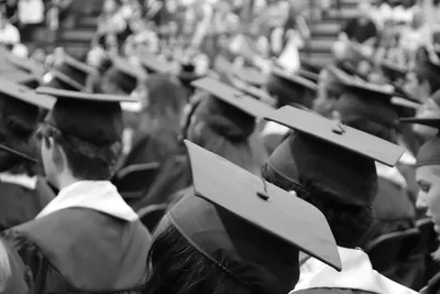 A black and white view of rows of graduates in square caps