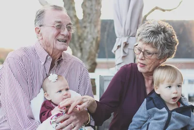Smiling grandparents holding a baby grandchild
