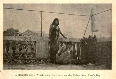 Old printed photo of a woman in a sari offering worship to a gudi on a terrace