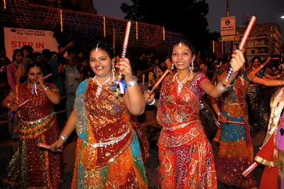 Women in red and gold chaniya choli dance garba with sticks
