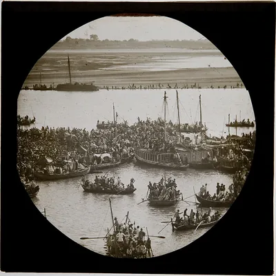 Old round photograph of boats and crowds at a riverside fair