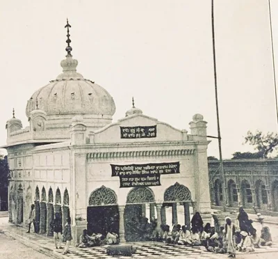 Old photo of a gurdwara with a white dome and arches