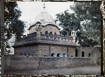 Early colour photo of a gurdwara with a white dome among trees