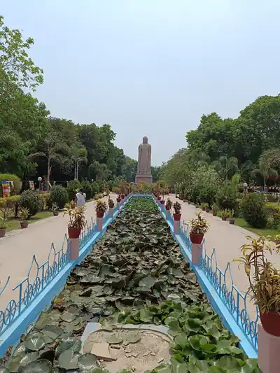 A long garden path with a lotus pool leading to a tall Buddha statue