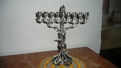 An ornate silver Hanukkah menorah on a lace cloth