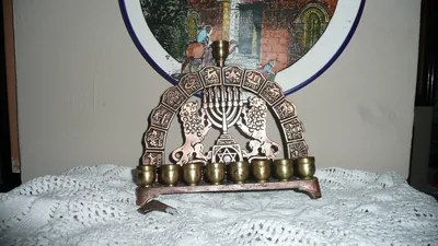 A brass menorah with oil cups in front of a decorated plate