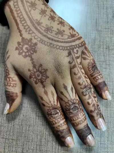 A hand with henna designs held up against a soft background
