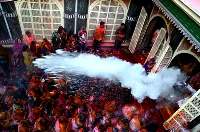 A jet of white water and colour sprayed over a packed temple courtyard