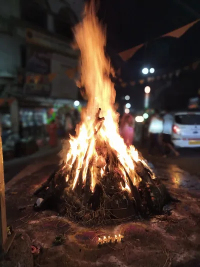 A bonfire blazes at night on a street lined with shops