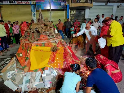 Families gather around a decorated pile of wood and cow dung cakes, offering prayers