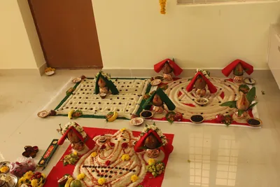Puja plates, kalash pots and patterns of rice and grains laid out on the floor for a new home