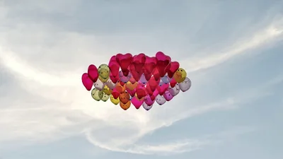 A bunch of heart shaped balloons floating in the sky