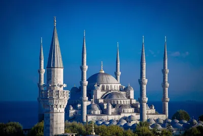 A mosque with many domes and slender minarets under a blue sky
