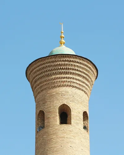 A round brick minaret with a small blue dome