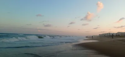 Waves rolling onto a long sandy beach at dusk