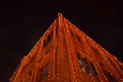 A tall building outlined with strings of small lights against the night sky
