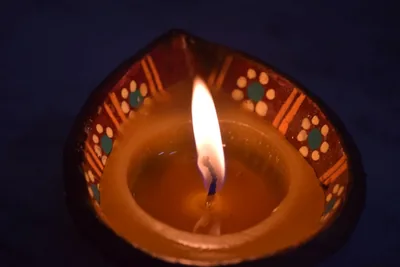 A painted clay lamp burning with a bright flame